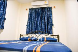 1 dormitorio con cama azul y cortinas azules en รีสอร์ทบ้านพระร่วง พระปรางค์ ศรีสัชนาลัย 