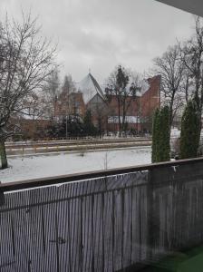 a snow covered park with a fence and buildings at Apartament Piłsudskiego in Szczytno