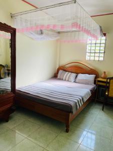 a bedroom with a bed with a canopy and a mirror at Bao Loc Homestay in Bao Loc