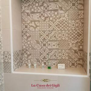 een badkamer met een wastafel en een betegelde muur bij La Casa dei Gigli in Lecce