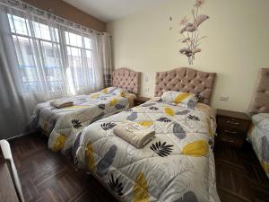 a bedroom with two beds and two windows at PAKARINA HOUSE in Cusco