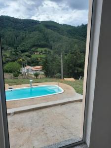 uma vista para uma piscina a partir de uma janela em Recanto do Sol em Joanópolis