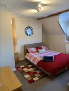 een slaapkamer met een bed met een klok aan de muur bij Studio Double. Own bathroom, shared kitchen in Bewdley