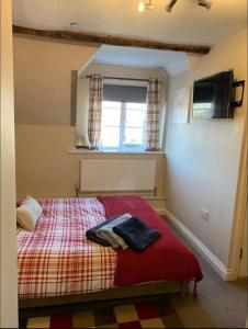 a bedroom with a bed with a red blanket and a window at Studio Double. Own bathroom, shared kitchen in Bewdley