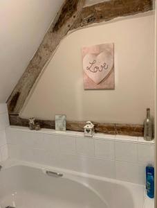 a bathroom with a bath tub with a sign that says love at Studio Double. Own bathroom, shared kitchen in Bewdley