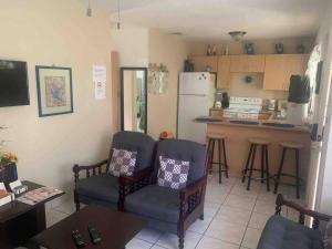 uma cozinha com 2 cadeiras e uma cozinha com um frigorífico em Villa de Ali in Palma real em La Ceiba