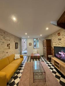a living room with a yellow couch and a tv at Cosy house in Casteljaloux