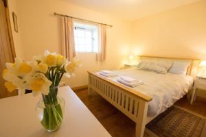 a bedroom with a bed with a vase of flowers on a table at Robins Nest in Buxton