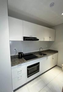 a white kitchen with a sink and a microwave at Departamento de 1 ambiente in Encarnación