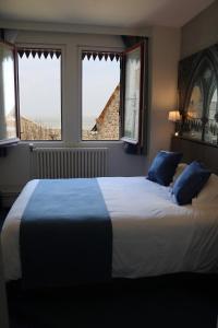 a bedroom with a large bed with two windows at Les Terrasses Poulard in Le Mont Saint Michel