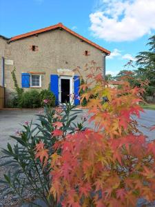 ein Haus mit blauen Türen und roten Blättern in der Unterkunft Gîte Marguerite - Au coeur de la campagne in La Petite-Boissière