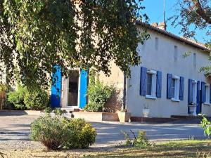 ein weißes Haus mit blauen Fenstern und einem Baum in der Unterkunft Gîte Marguerite - Au coeur de la campagne in La Petite-Boissière