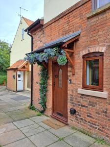a brick building with a door with flowers on it at Willow's Cottage in Edwinstowe
