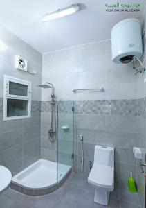 a bathroom with a shower and a toilet and a sink at Bahjat Al Azaiba Villa in Muscat