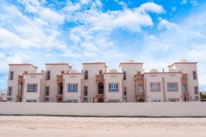 a large white building behind a white fence at Bahjat Al Azaiba Villa in Muscat