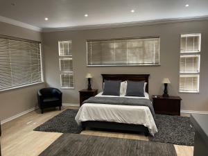 Schlafzimmer mit einem Bett, einem Stuhl und Fenstern in der Unterkunft Grants Hill Inn in Bloemfontein