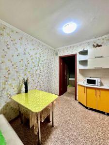 eine Küche mit einem gelben Tisch in einem Zimmer in der Unterkunft Аренда с Самостоятельным Заездом in Pawlodar