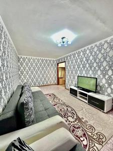 ein Wohnzimmer mit einem Sofa und einem Flachbild-TV in der Unterkunft Аренда с Самостоятельным Заездом in Pawlodar