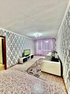 ein Wohnzimmer mit einem Sofa und einem TV in der Unterkunft Аренда с Самостоятельным Заездом in Pawlodar