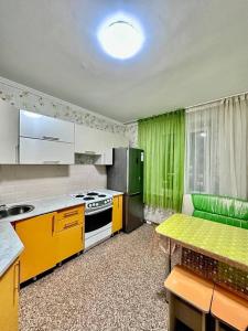 a kitchen with yellow and green cabinets and a table at Аренда с Самостоятельным Заездом in Pavlodar