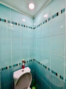 baño con aseo y pared de azulejos azules en Аренда с Самостоятельным Заездом, en Pavlodar