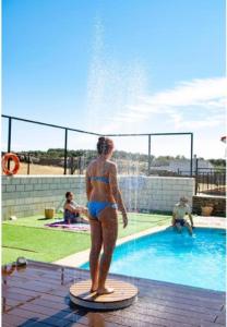 a woman in a bathing suit standing next to a swimming pool at Apartamento Loft La Encina in Torrejón el Rubio