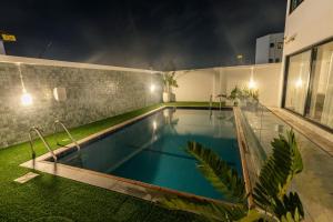 een zwembad in de achtertuin van een huis 's nachts bij The Valley Villa in Accra