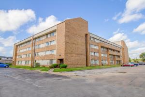 a large brick building with cars parked in a parking lot at Tulsa Square Hotel Central, I-44 By OYO in Tulsa