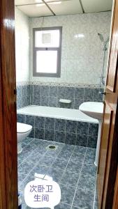 a bathroom with a tub and a toilet and a sink at Ms. Zhang Apartment in Abu Dhabi