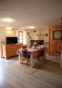 ein Esszimmer mit einem Tisch, Stühlen und einem TV in der Unterkunft Maison Chez Les Roset in Baulen