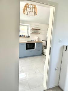 a kitchen with blue cabinets and a white tile floor at Novo uređeni apartman sa velikom terasom in Vis