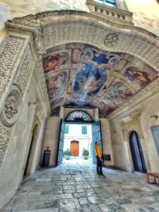 a person standing in a building with a ceiling with paintings at Saint patrick guest house in Barletta