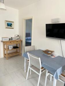 a dining room with a table and chairs and a television at Novo uređeni apartman sa velikom terasom in Vis