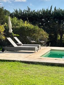una piscina con una silla y una sombrilla junto a una piscina en Charmante maisonnette avec jardin et piscine en Aix-en-Provence