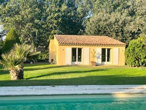una pequeña casa amarilla en un patio junto a un cuerpo de agua en Charmante maisonnette avec jardin et piscine en Aix-en-Provence