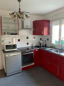 uma cozinha com armários vermelhos e electrodomésticos brancos em GRAND APPARTEMENT AVEC TERRASSE & JARDIN A 5 minutes de PARIS em Cachan