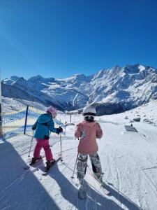 2 enfants à skis dans la neige sur une piste de ski dans l'établissement Ski-In/Ski-Out Hotel Sport, à Saas-Almagell