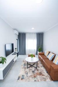 a living room with a couch and a table at Luxe Lumiere @ The Habitat Alpha in Gaborone