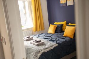 Schlafzimmer mit einem Bett mit gelben und blauen Kissen in der Unterkunft Exclusive house for contractors and families in Buttershaw