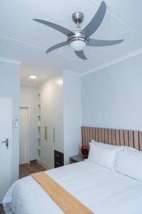 a bedroom with a ceiling fan and a white bed at Luxe Lumiere @ The Habitat Alpha in Gaborone