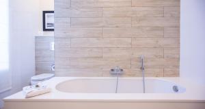 a white bathroom with a tub and a toilet at Salini Resort in St. Paul's Bay