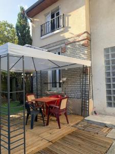 eine Terrasse mit einem Tisch und Stühlen unter einem weißen Schirm in der Unterkunft PAVILLON & Jardinet A 5 MN PARIS , 30 MN STADE de FRANCE au pied du RER B in Cachan