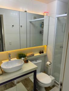 uma casa de banho com um lavatório, um WC e um espelho. em Apto alto padrão em Florianópolis em Florianópolis