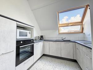 cocina blanca con microondas y ventana en Le Parc du Moulin, en Montfermeil