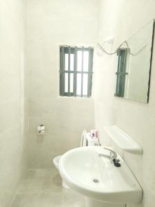 a white bathroom with a sink and a mirror at Barro luxury in Cotonou