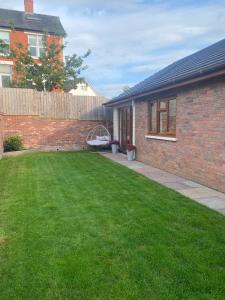 a yard with a brick house and a fence at Dave & Kelz Deluxe king size studio room in Builth Wells