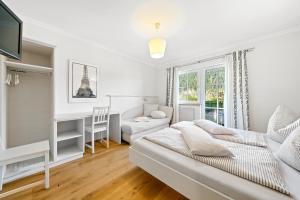 a white bedroom with a bed and a desk at Appartement Ferienhof Ortnergut in Eben im Pongau