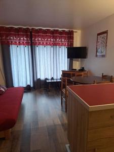ein Wohnzimmer mit einem roten Sofa und einem Tisch in der Unterkunft Studio douillet aux deux Alpes in Les Deux Alpes