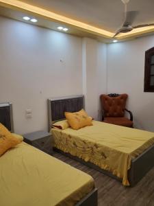 a room with two beds and a chair at Cosy appartment in city in Luxor