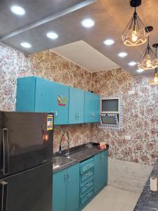 a kitchen with blue cabinets and a black refrigerator at Cosy appartment in city in Luxor